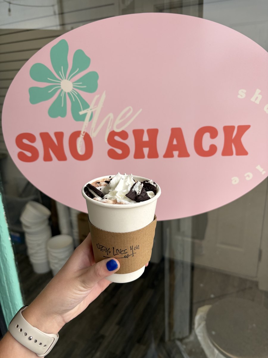 A dirty soda topped with whipped cream and cookie pieces, held at the window
